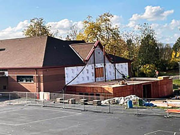 a building under construction with a one story partial building attached to an existing 2-story building